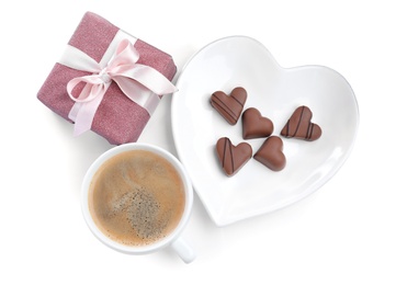 Photo of Romantic breakfast with cup of coffee, chocolate candies and gift box on white background, top view. Valentine's day celebration