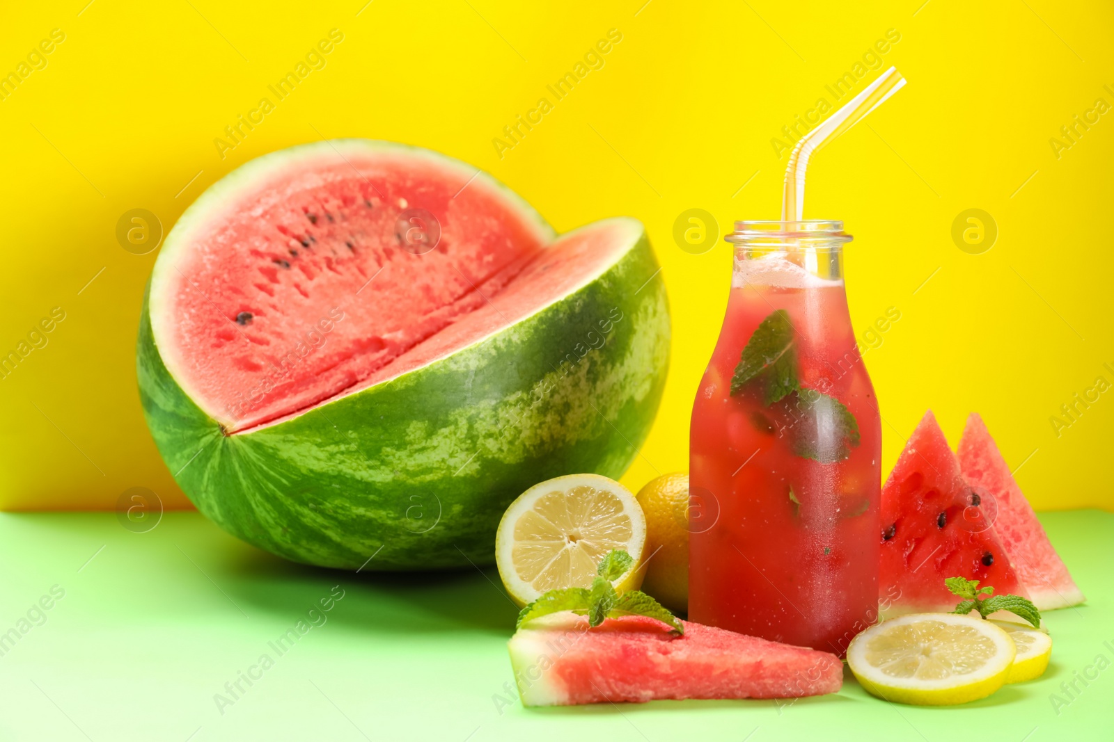Photo of Tasty watermelon drink and fresh fruits on green table against yellow background