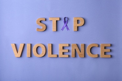 Photo of Flat lay composition with purple ribbon and words STOP VIOLENCE on violet background. Awareness day