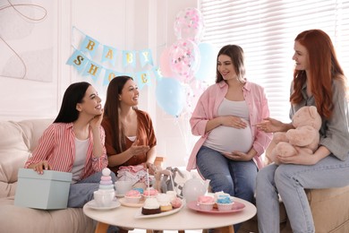 Photo of Happy pregnant woman spending time with friends at baby shower party