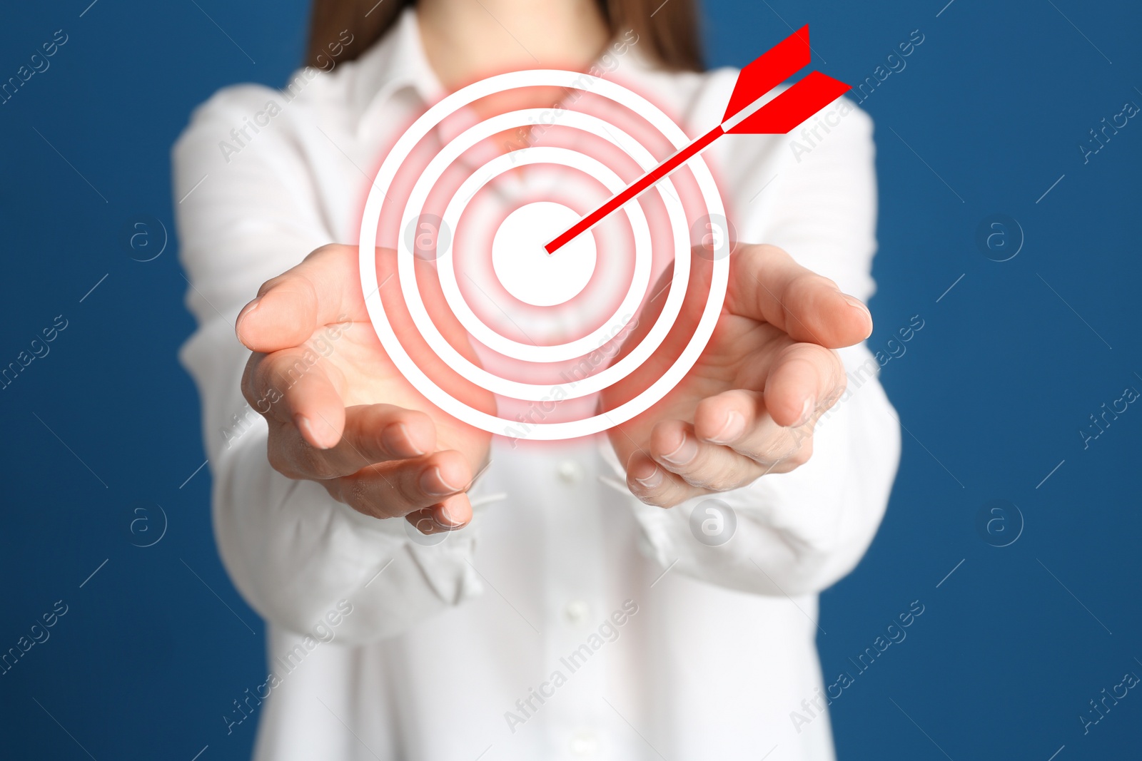 Image of Young woman and dartboard on blue background, closeup