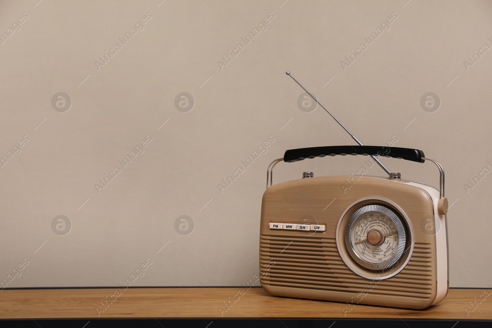 Photo of Retro radio receiver on wooden table against grey background. Space for text