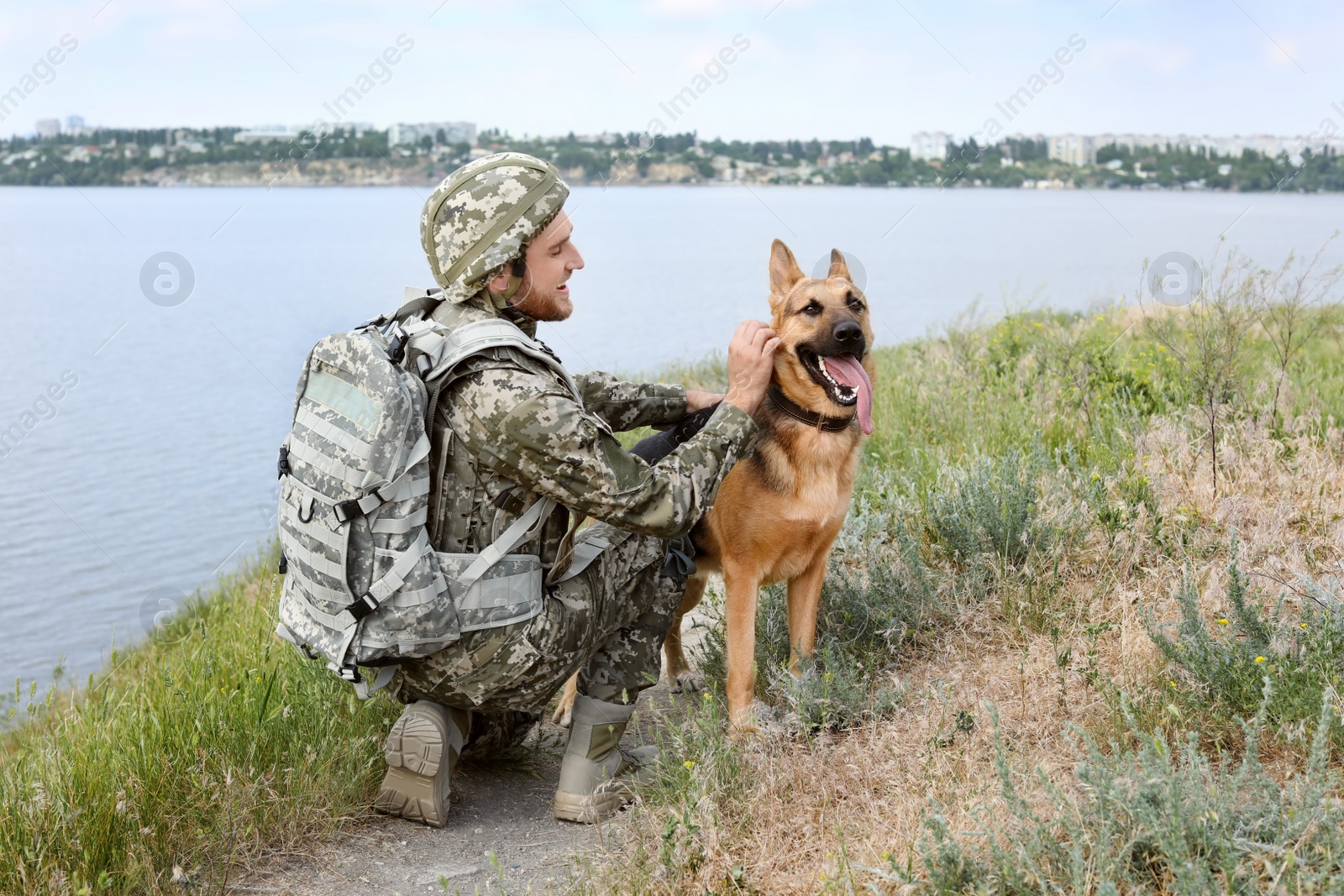 Photo of Man in military uniform with German shepherd dog outdoors