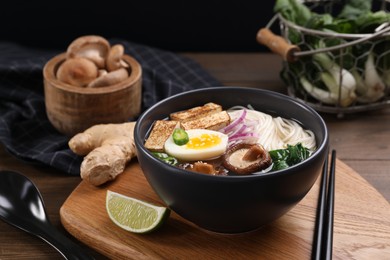 Delicious vegetarian ramen in bowl and products on wooden table