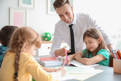 Male teacher helping girl with her task in classroom at school