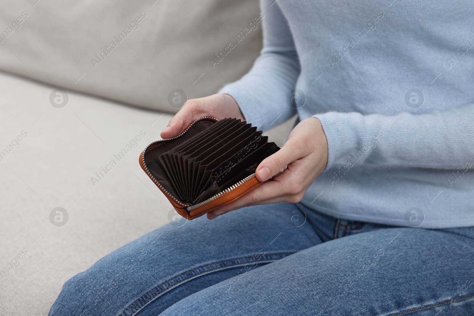 Photo of Woman with empty wallet on sofa indoors, closeup