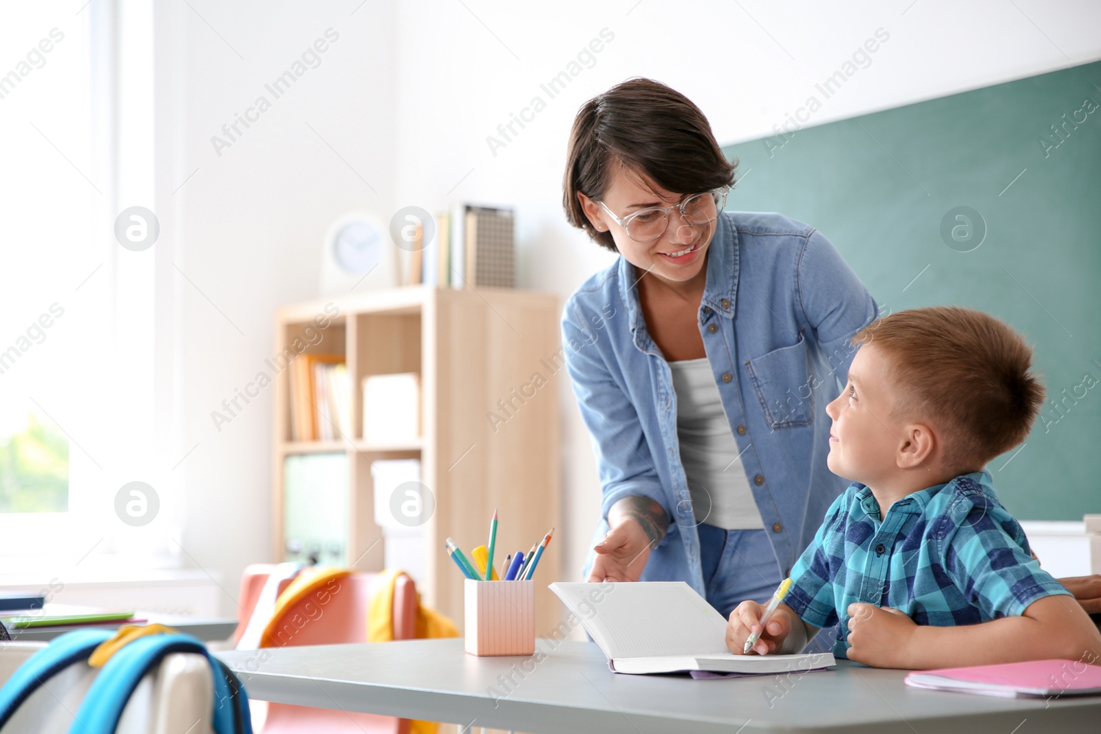 Photo of Female teacher helping child with assignment at school