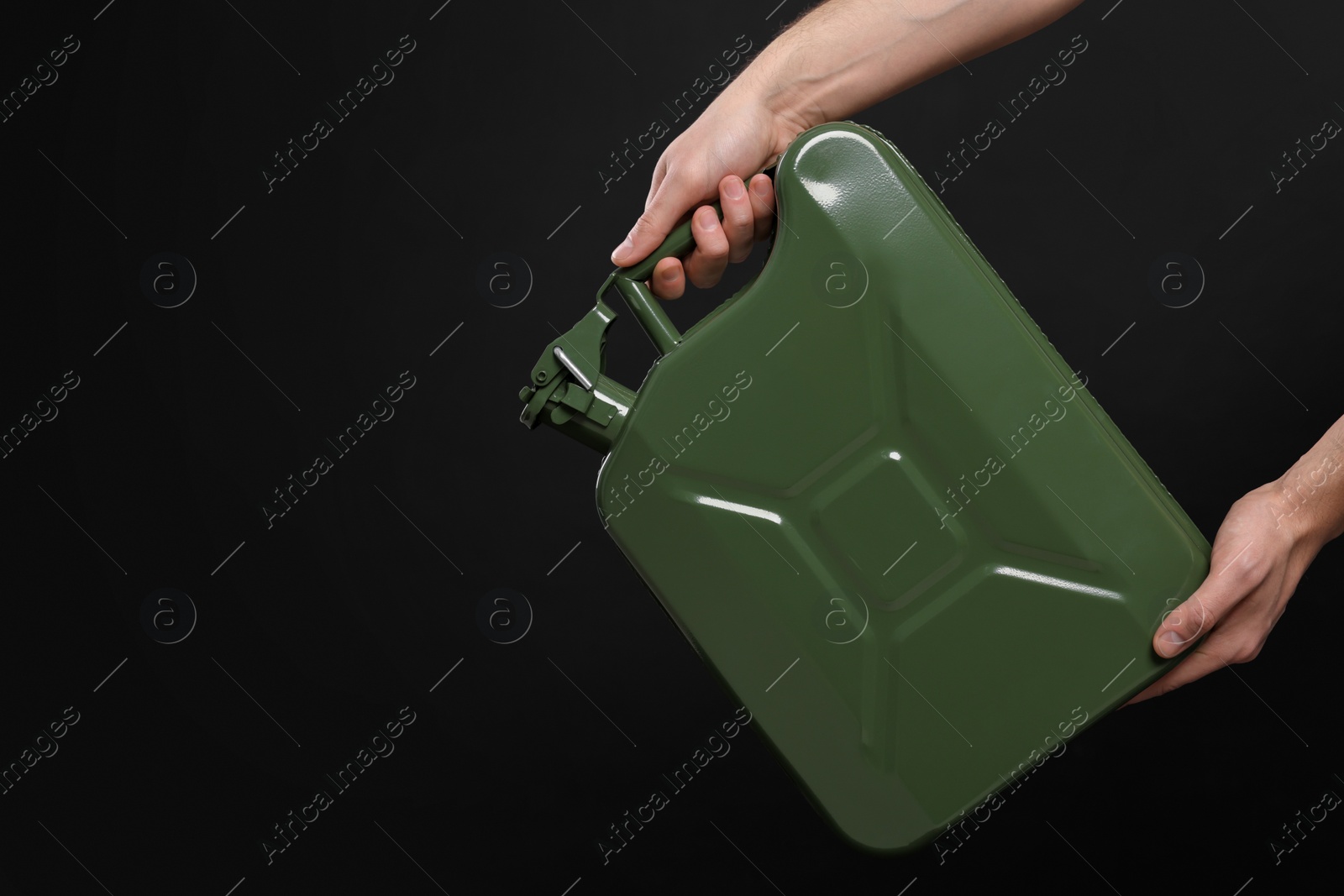 Photo of Man holding khaki metal canister on black background, closeup. Space for text