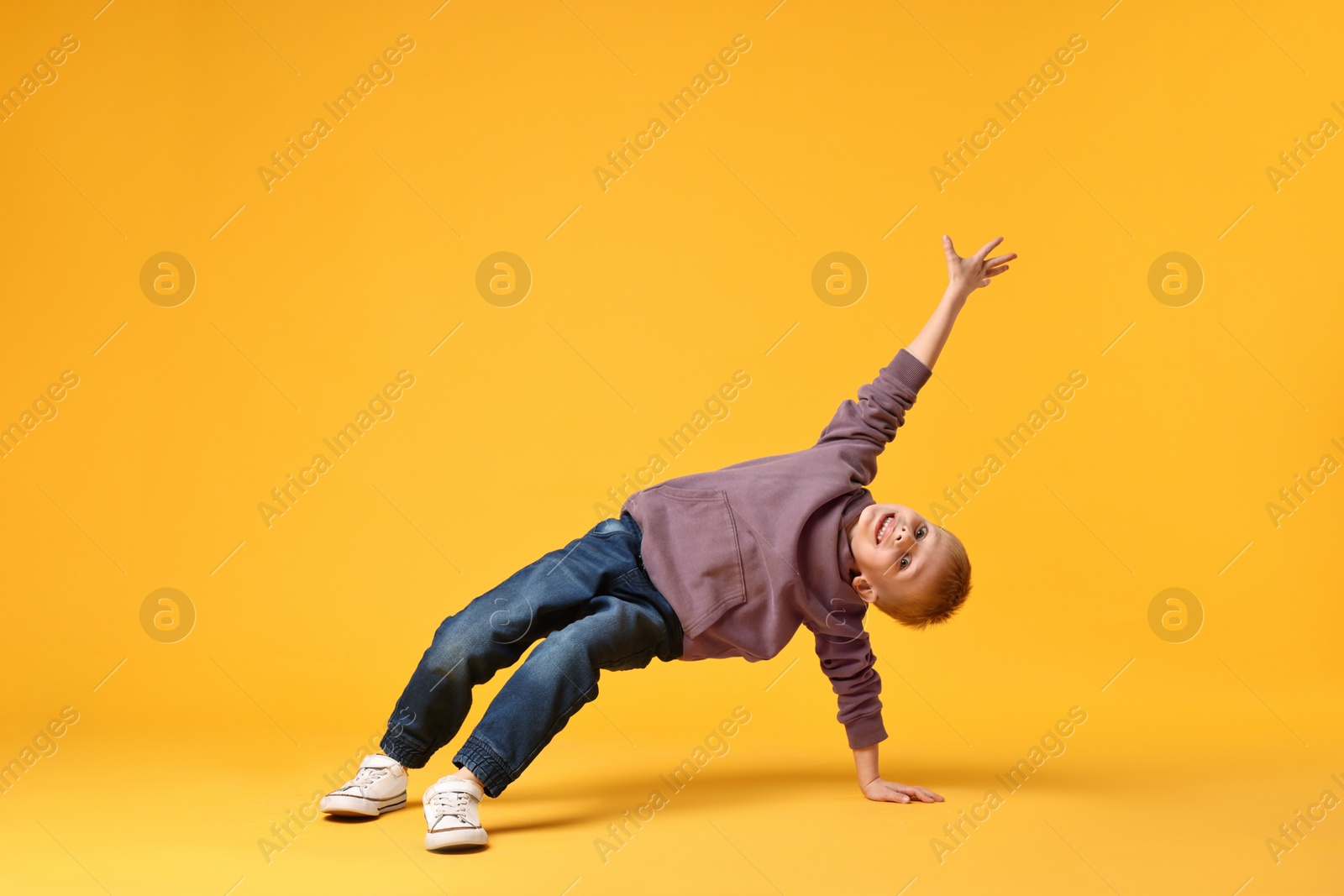 Photo of Happy little boy dancing on yellow background