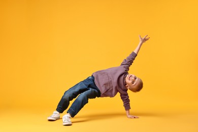 Happy little boy dancing on yellow background