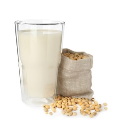 Photo of Glass of fresh soy milk and sack bag with beans on white background