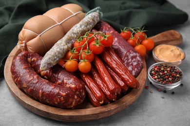 Different types of tasty sausages and ingredients on light grey table