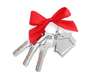 Keys with keychain in shape of house and red bow isolated on white, top view