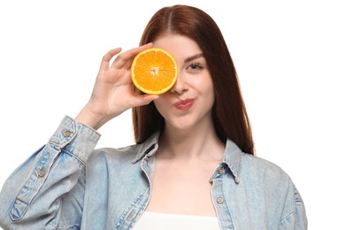 Beautiful woman covering eye with half of orange on white background