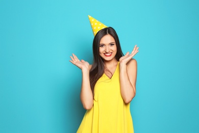 Young woman with party cap on color background. Birthday celebration