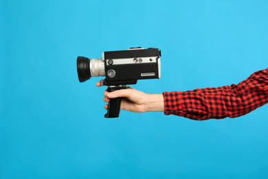 Woman with vintage video camera on light blue background, closeup of hand