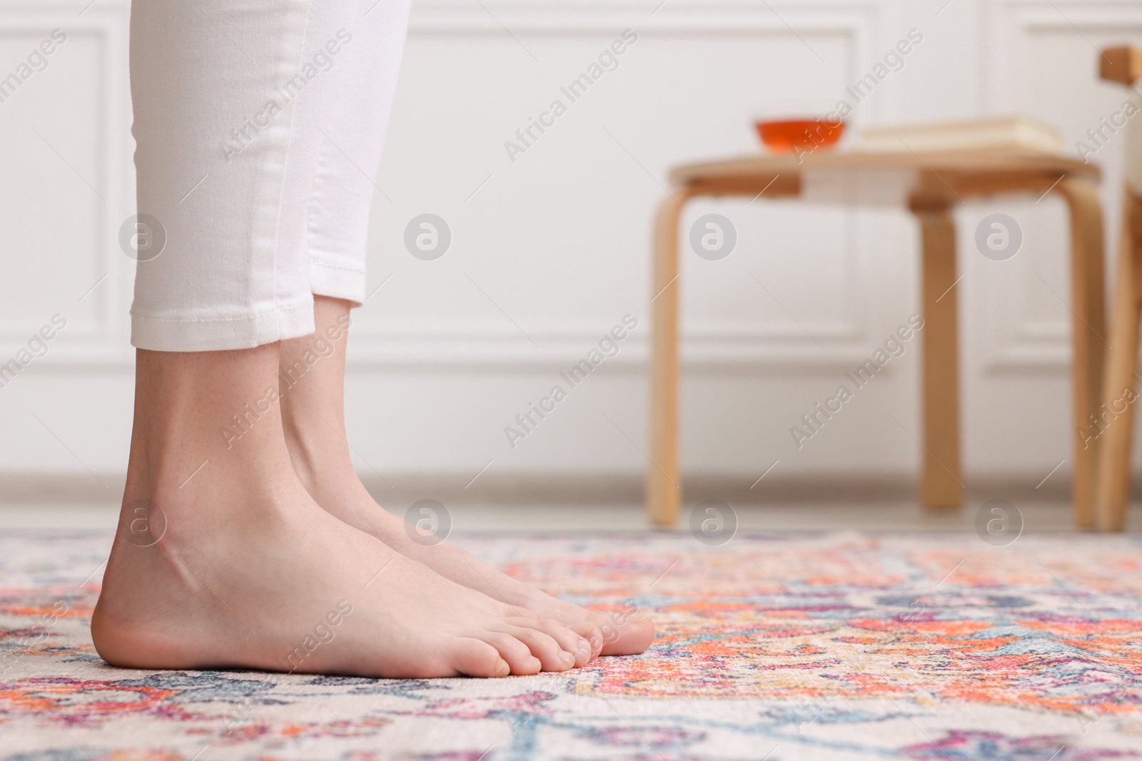 Photo of Woman standing on carpet with pattern at home, closeup. Space for text