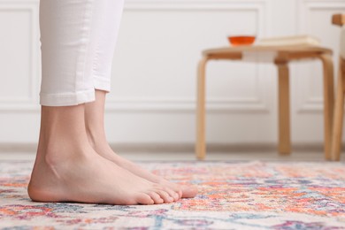 Woman standing on carpet with pattern at home, closeup. Space for text