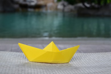 Photo of Beautiful yellow paper boat on wicker sunbed outdoors