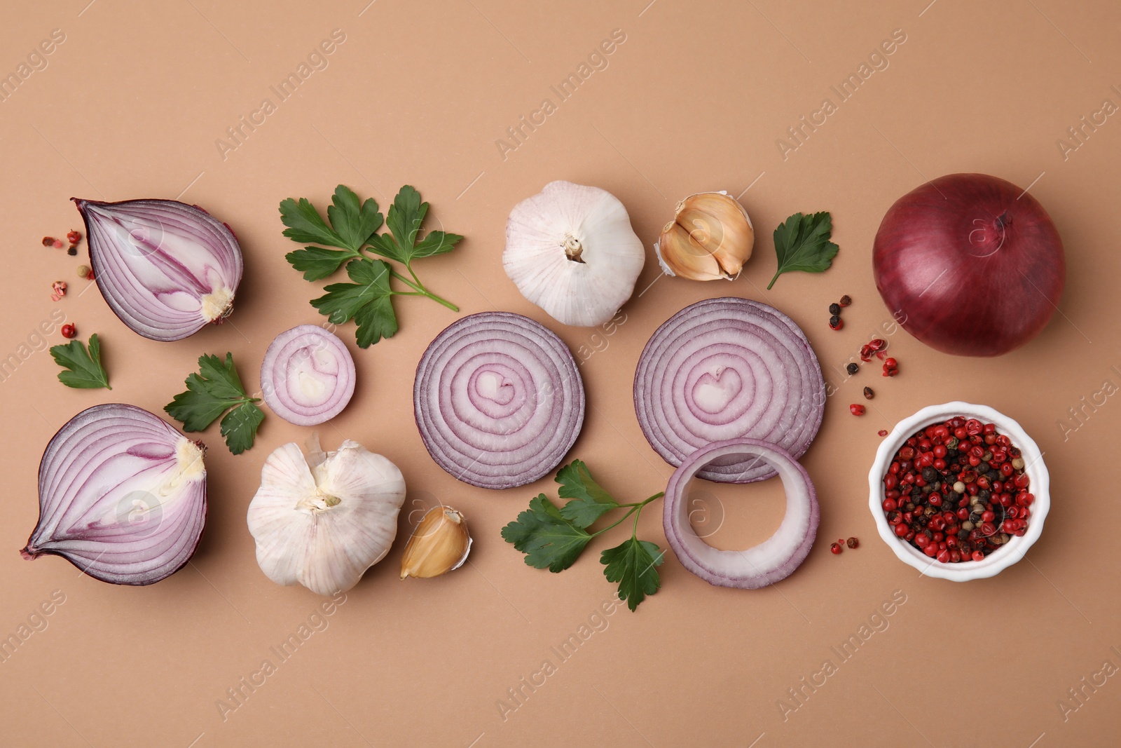 Photo of Fresh red onions, garlic, parsley and spices on beige background, flat lay