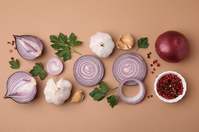 Photo of Fresh red onions, garlic, parsley and spices on beige background, flat lay