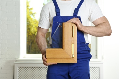 Installation worker with sample of modern window profile indoors