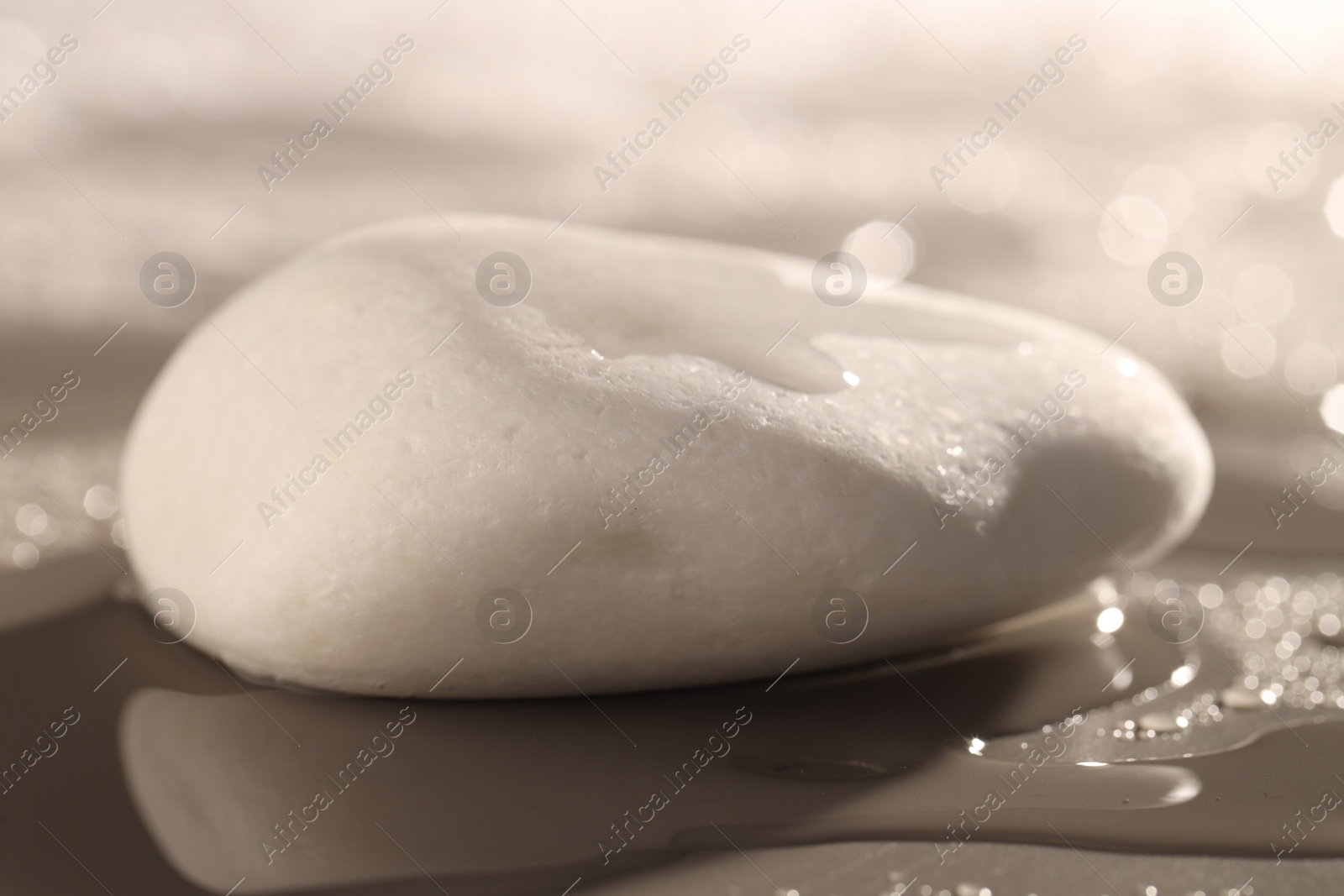 Photo of White spa stone with water drops on grey background, closeup