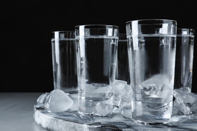 Photo of Vodka in shot glasses and ice on grey table, closeup