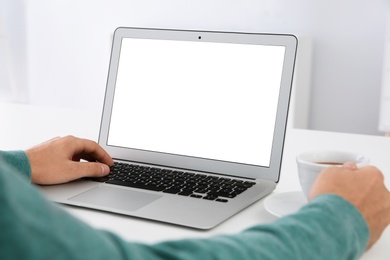 Photo of Young man working with modern laptop at table, closeup. Mockup for design
