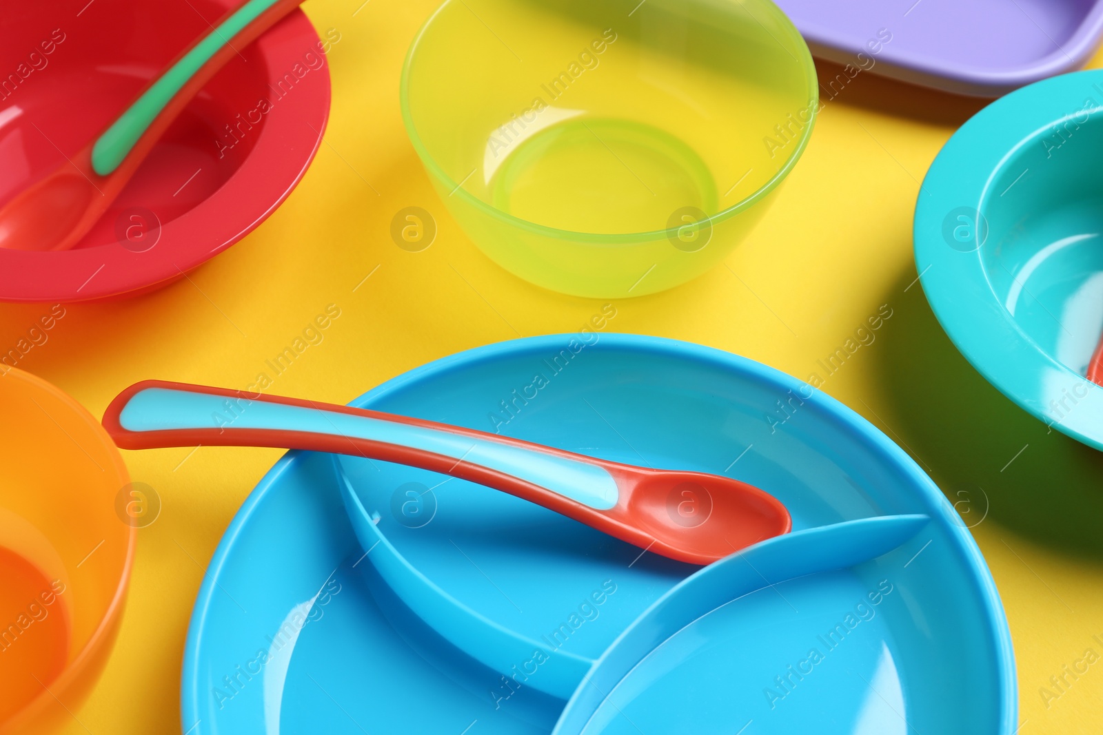 Photo of Set of colorful plastic dishware on yellow background. Serving baby food