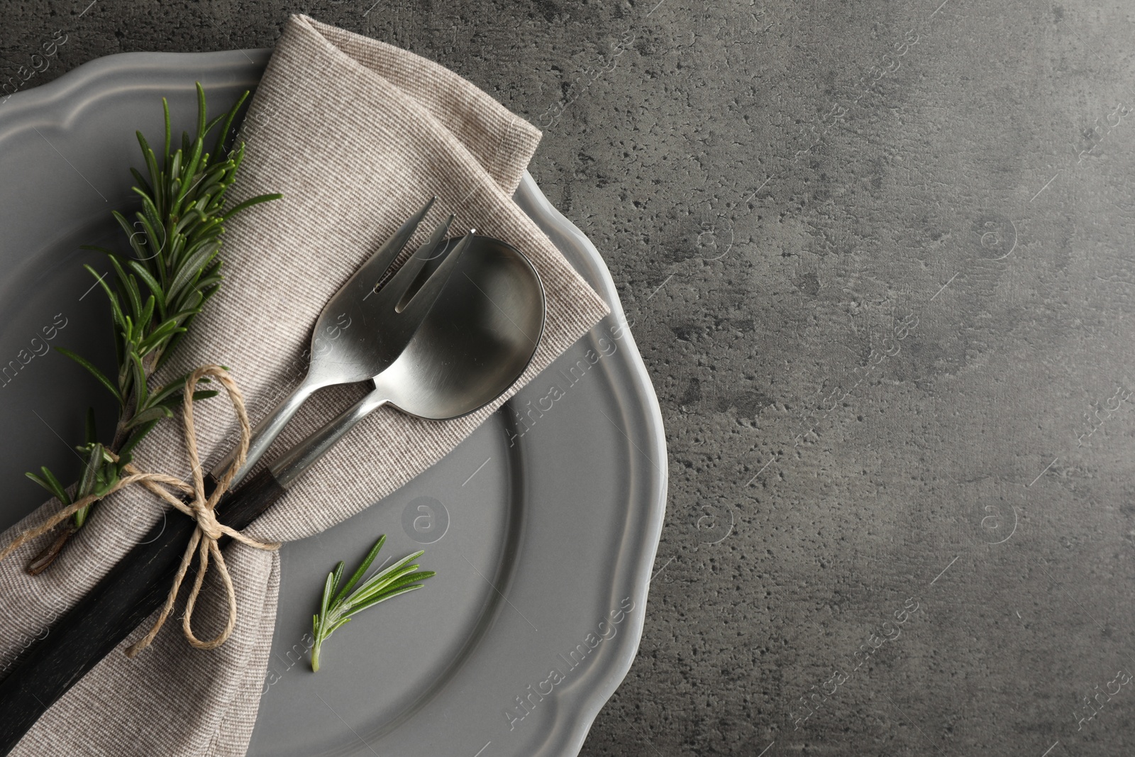 Photo of Stylish setting with cutlery and napkin on black table, top view. Space for text