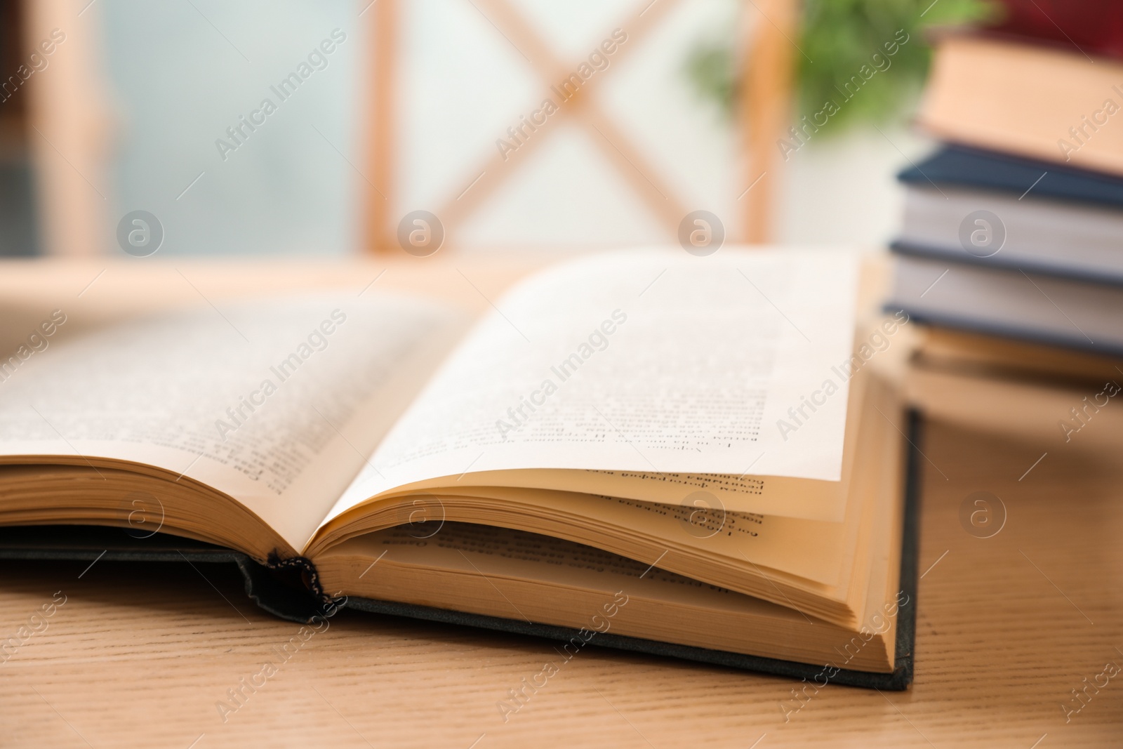 Photo of Open hardcover book on wooden table indoors, closeup