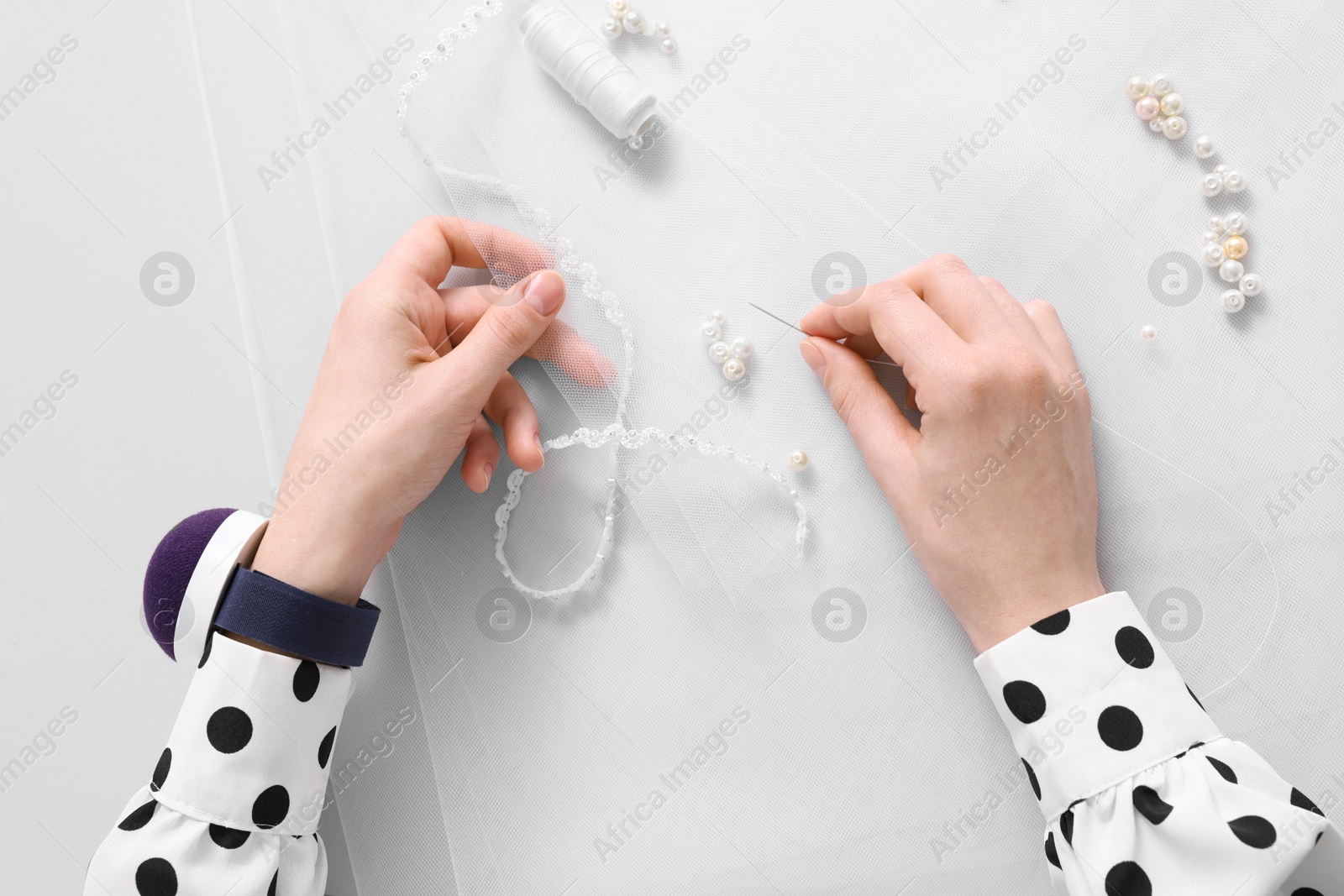 Photo of Dressmaker with sewing accessories at white table, top view