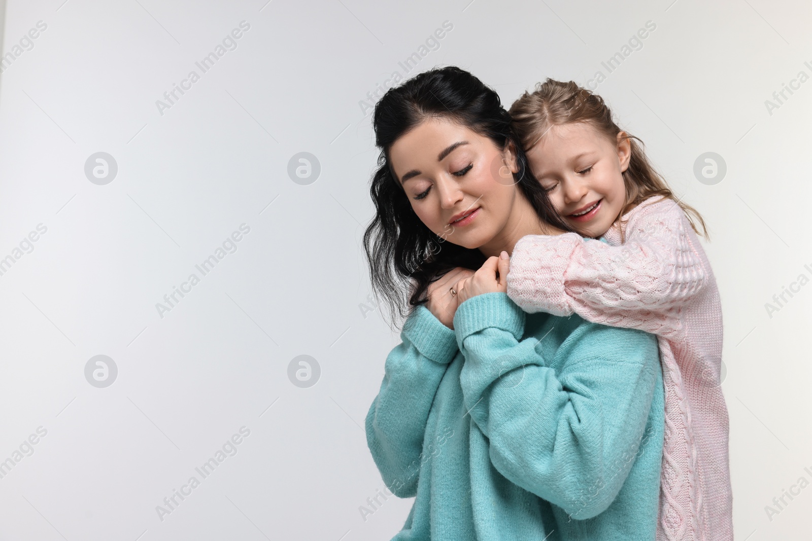 Photo of Beautiful mother hugging with little daughter on white background. Space for text