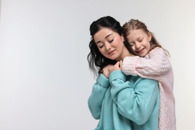 Beautiful mother hugging with little daughter on white background. Space for text