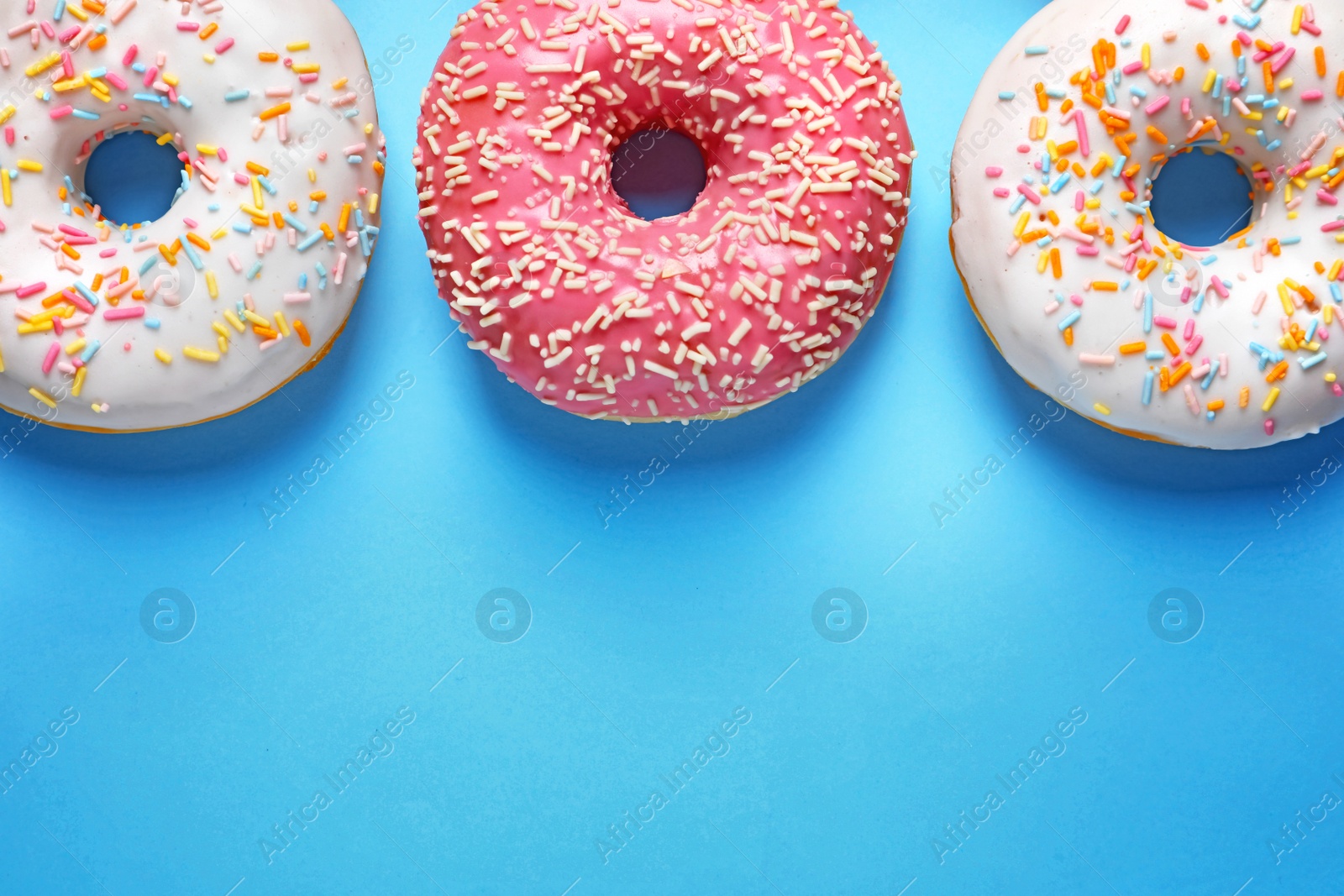 Photo of Delicious glazed doughnuts on color background, top view