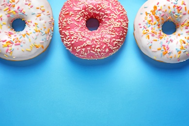 Delicious glazed doughnuts on color background, top view