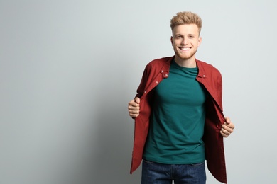 Photo of Young man wearing blank t-shirt on light background. Mockup for design