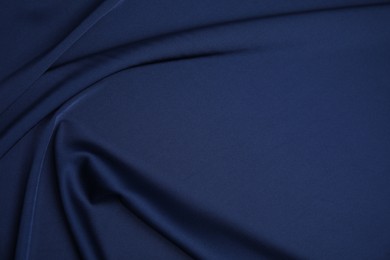 Crumpled dark blue silk fabric as background, top view. Space for text