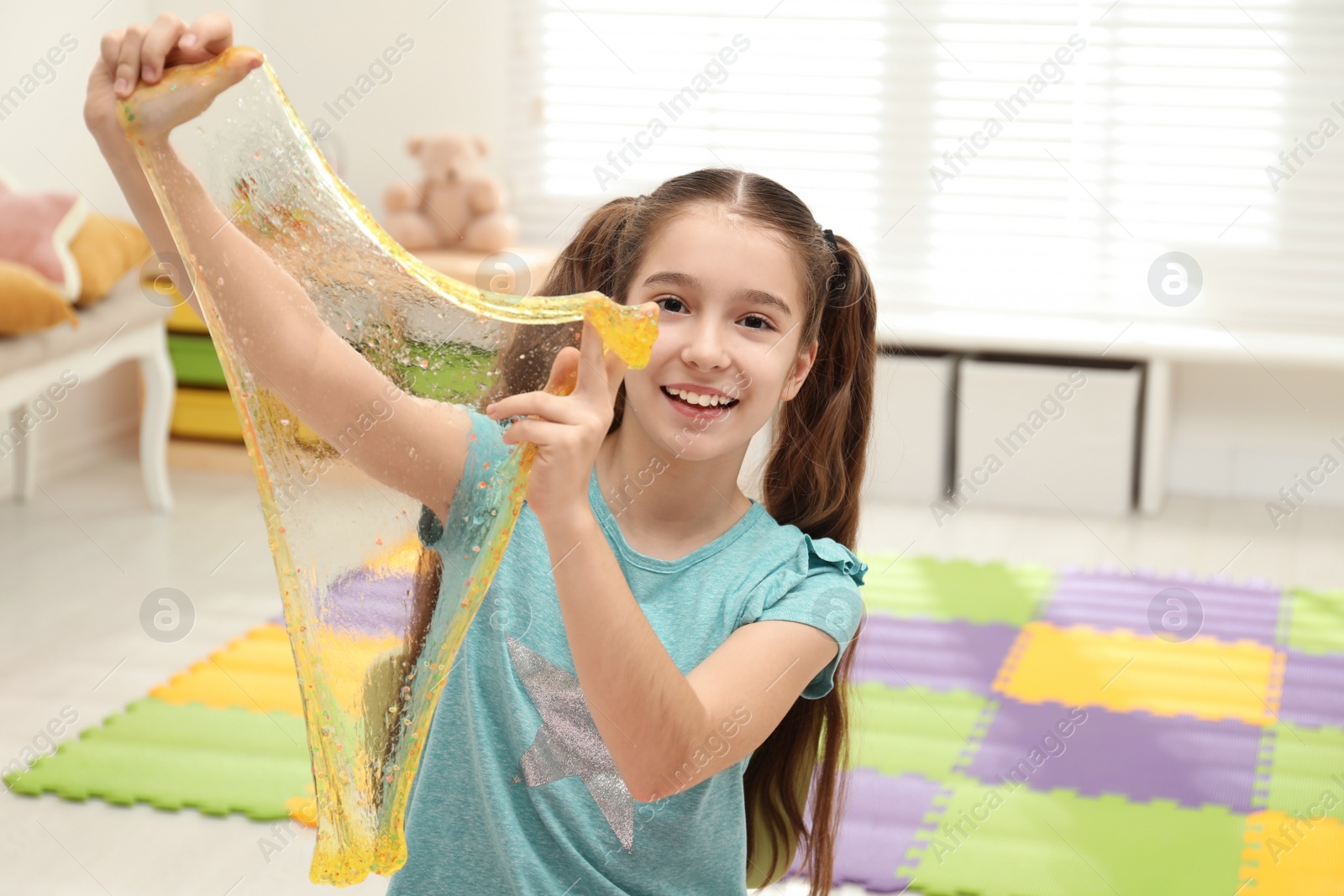 Photo of Preteen girl playing with slime in room