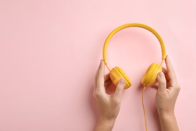 Photo of Woman holding headphones on color background, top view. Space for text