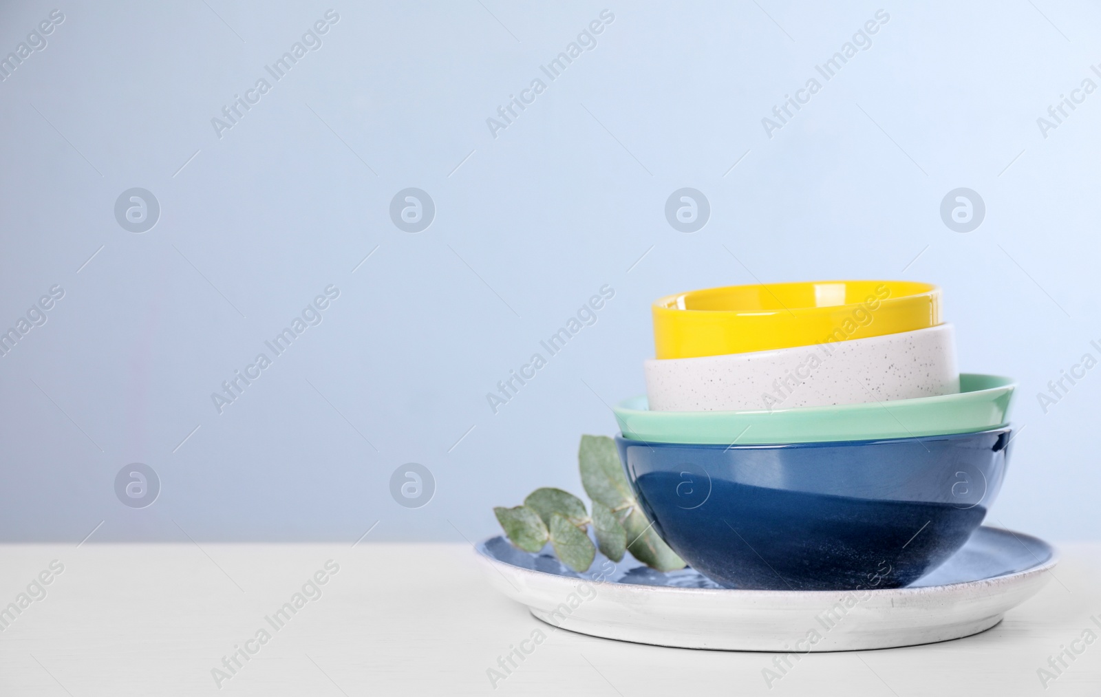 Photo of Set of clean tableware on light table. Space for text