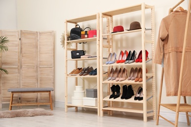 Photo of Wooden shelving unit with different shoes and accessories in stylish room interior