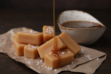 Photo of Pouring caramel on candies with sea salt at table, closeup