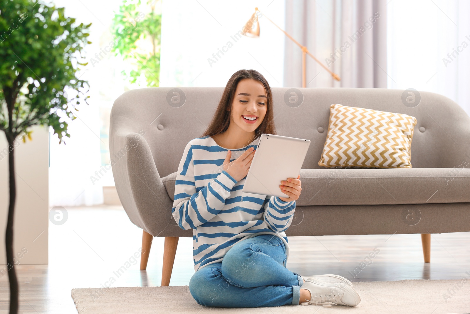 Photo of Woman using tablet for video chat in living room