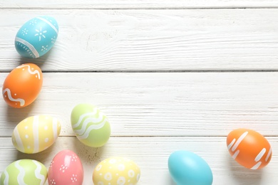 Photo of Flat lay composition with painted Easter eggs on wooden background, space for text