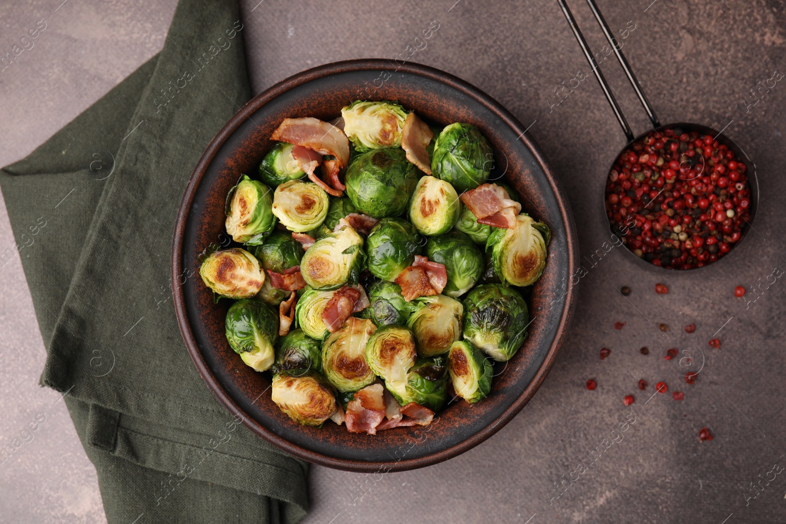 Photo of Delicious roasted Brussels sprouts, bacon and peppercorns on brown table, top view