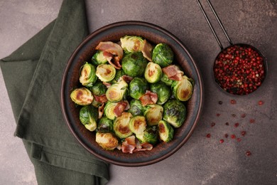 Delicious roasted Brussels sprouts, bacon and peppercorns on brown table, top view