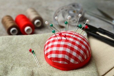 Photo of Pincushion, spools of threads and sewing tools on table, closeup