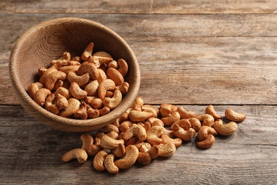 Tasty cashew nuts scattered from bowl on table